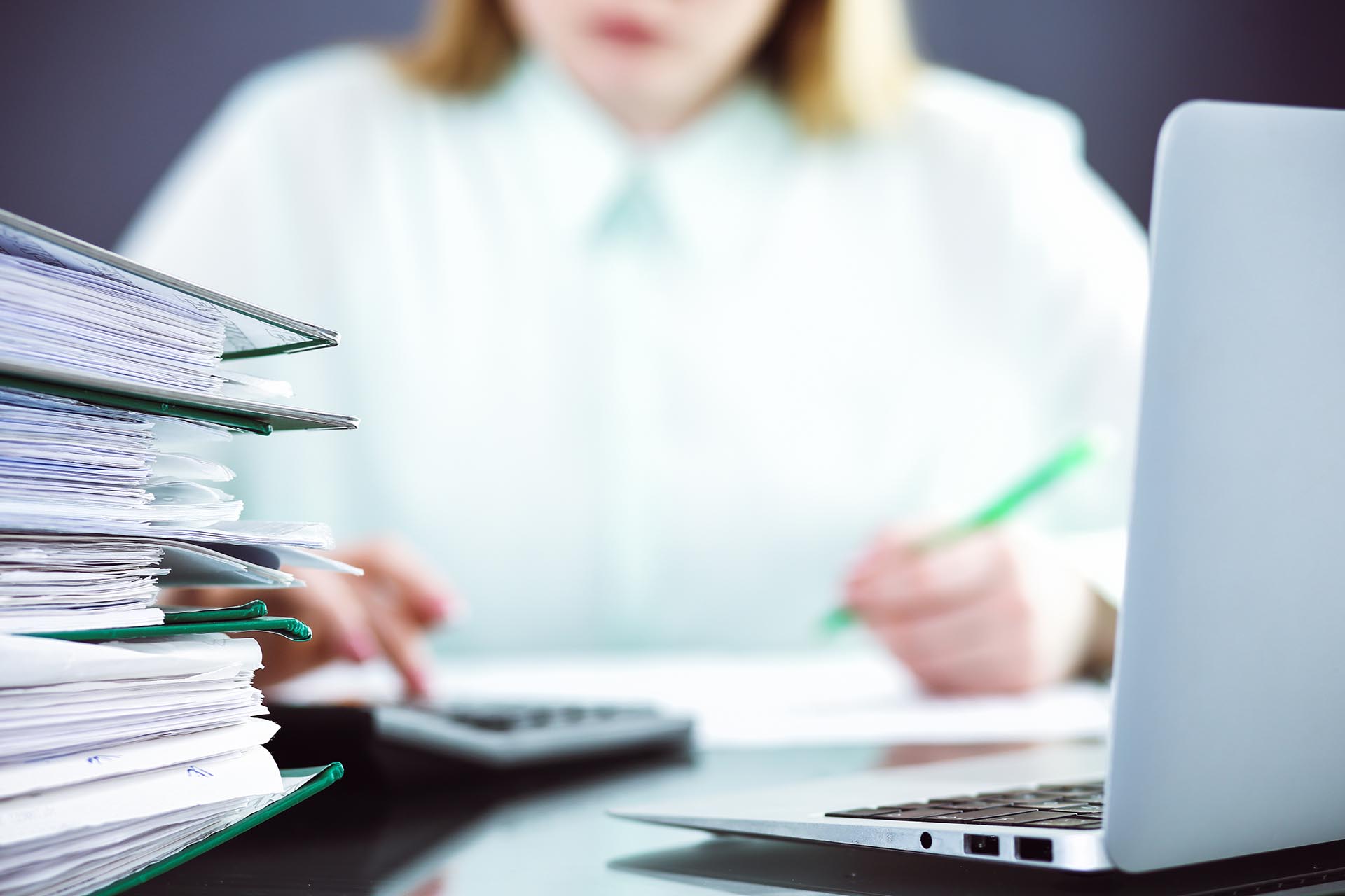 Frau am Schreibtisch mit Steuerdokumenten und Computer, Fokus auf Steuerplanung und -organisation